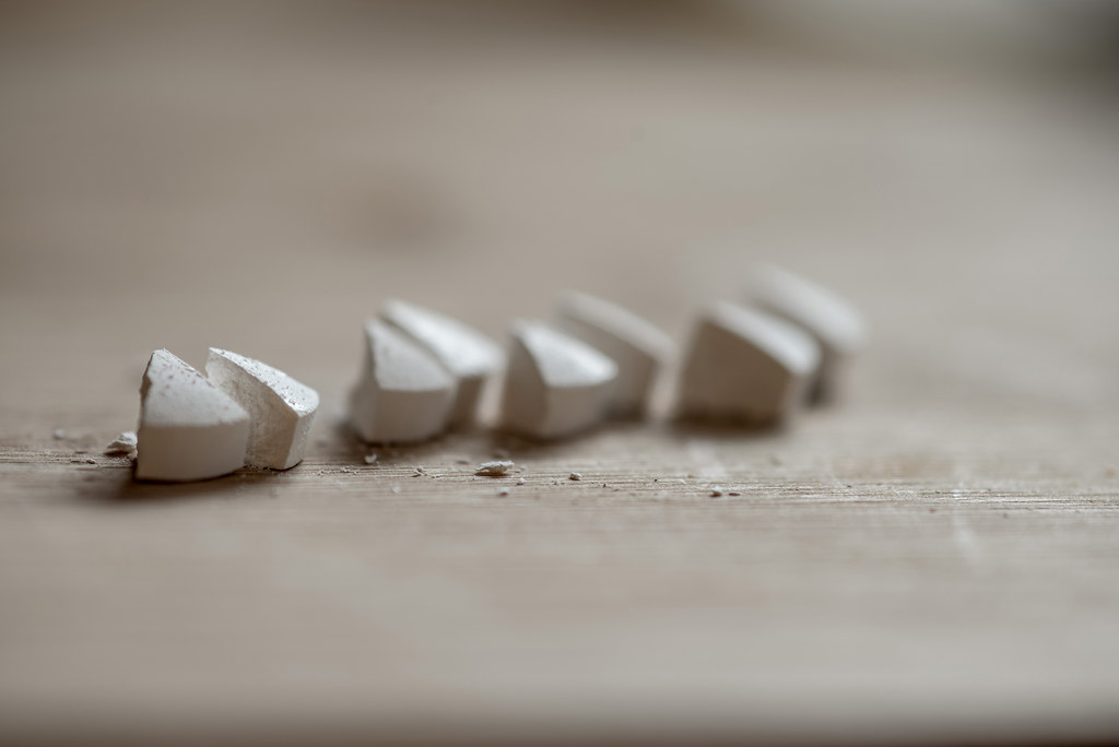 Row of white lozenge tablets on a wooden table